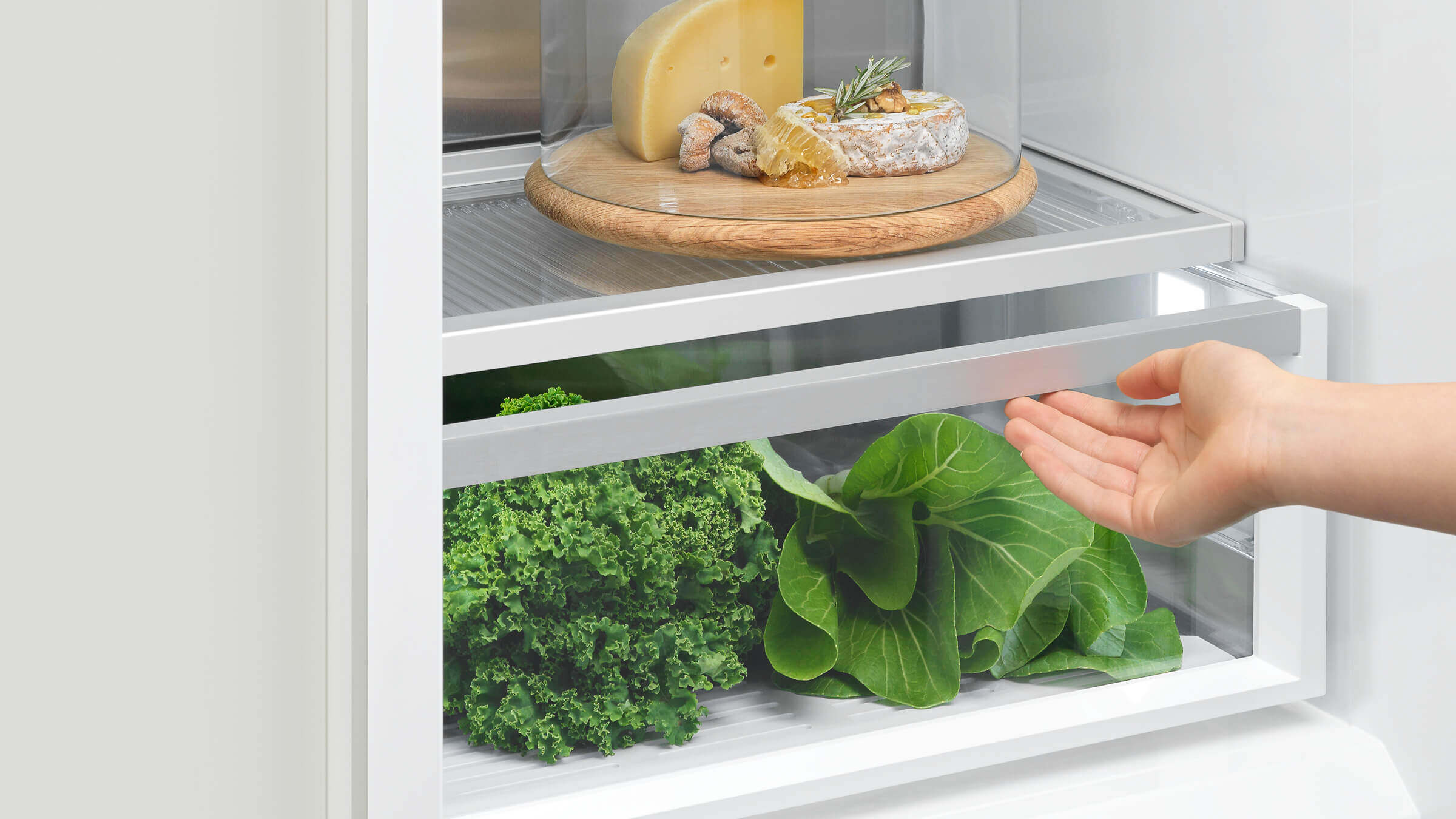 A hand reaching into an illuminated refrigerator column, highlighting easy access